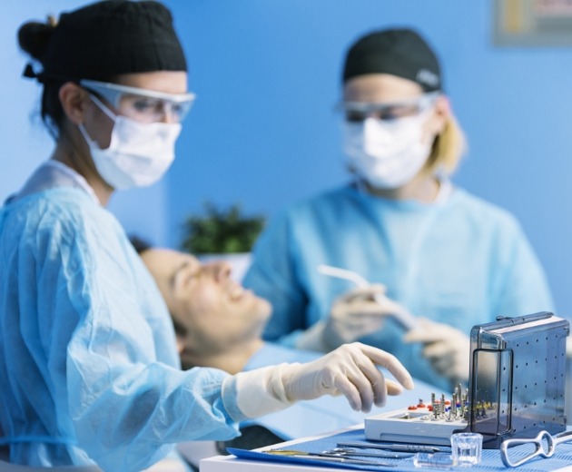 Oral surgeon reaching for surgical tool during procedure