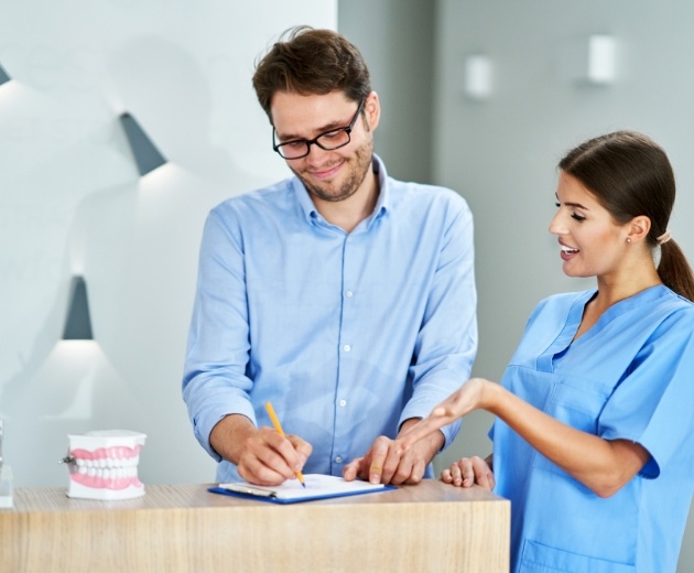 Oral surgery team member showing a man where to sign on a clipboard