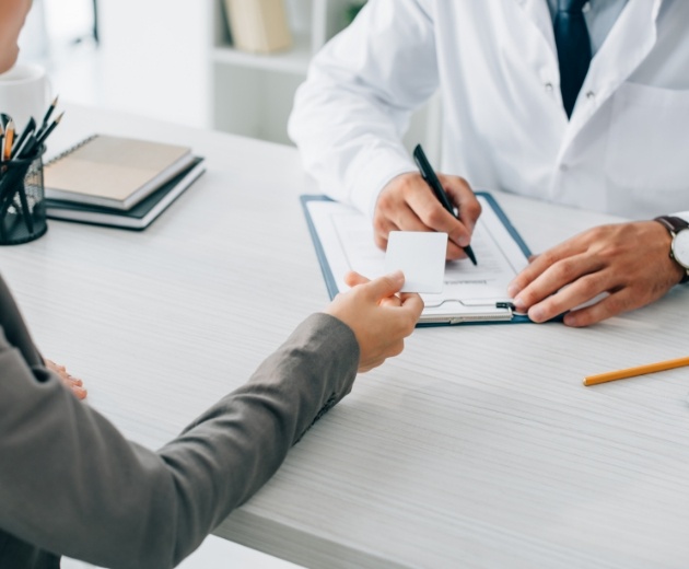 Patient handing an insurance card to her oral surgeon