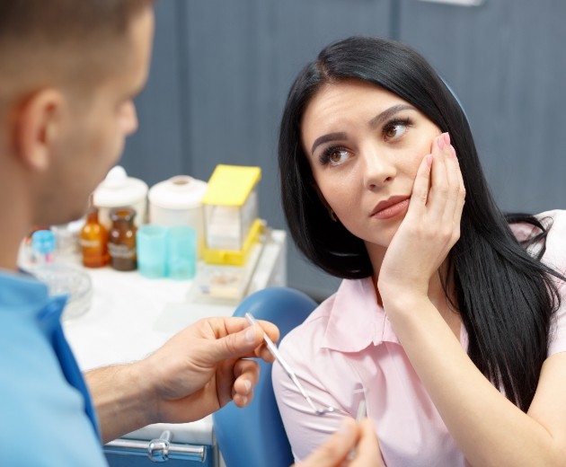 Woman holding her jaw in pain while talking to Reston oral surgeon