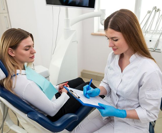 Dental team member making notes on clipboard