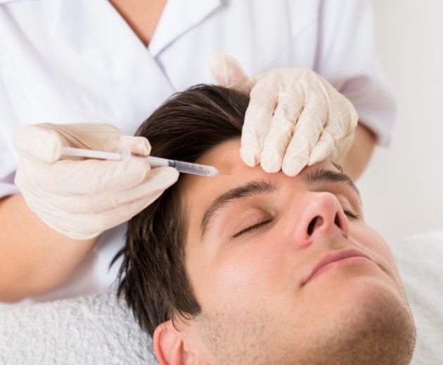 Man with eyes closed receiving Botox cosmetic treatment from Reston oral surgeon