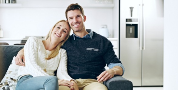 Young man and woman smiling together on couch