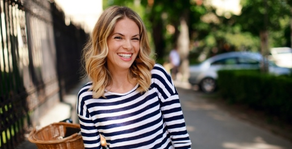 Blonde woman in striped blouse smiling outdoors