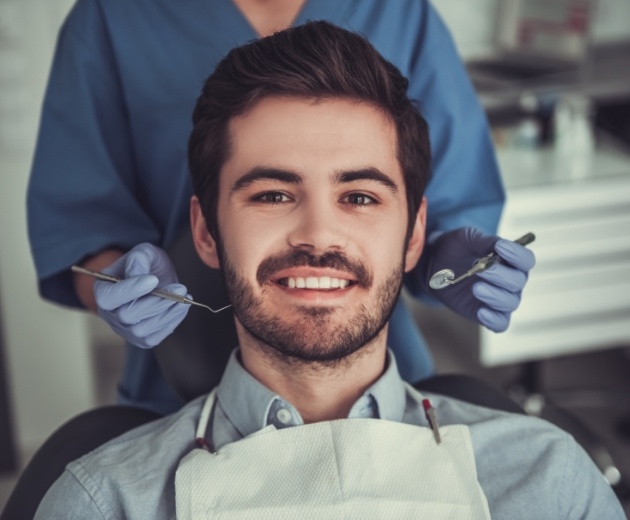 Young man with short beard smiling in dental chair