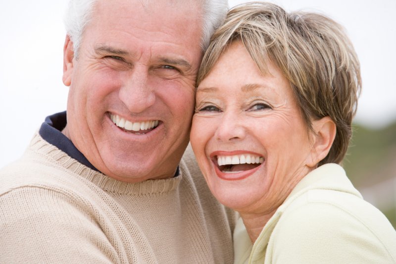 Elderly couple smiling widely standing closely together